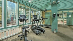 A gym with treadmills, stationary bikes, and a fan.
