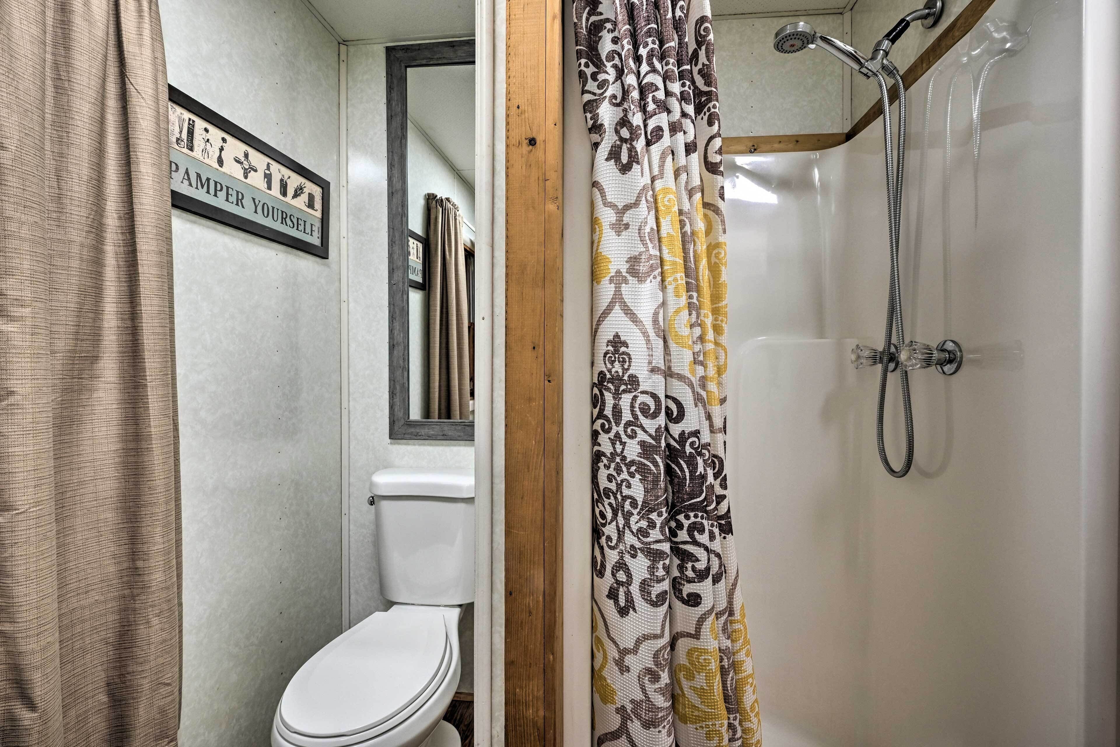 A bathroom with a toilet, shower, and a sign that reads "PAMPER YOURSELF!"
