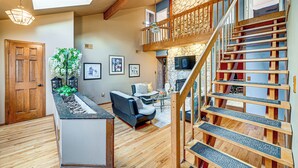 Un vaste espace de vie agrémenté d’un escalier en bois, d’une cheminée et d’un coin salon.