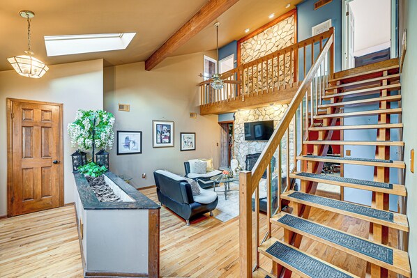 A spacious living area with a wooden staircase, a fireplace, and a seating area. - < 1 Mi to Ocean Gate Beach! Lovely Home w/ Hot Tub (Ocean Gate)