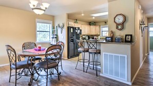 A kitchen with a dining area, wooden cabinets, a refrigerator, a clock, and a chandelier. - Ruidoso Home w/ Deck & Grill, Near Grindstone Lake (Ruidoso)