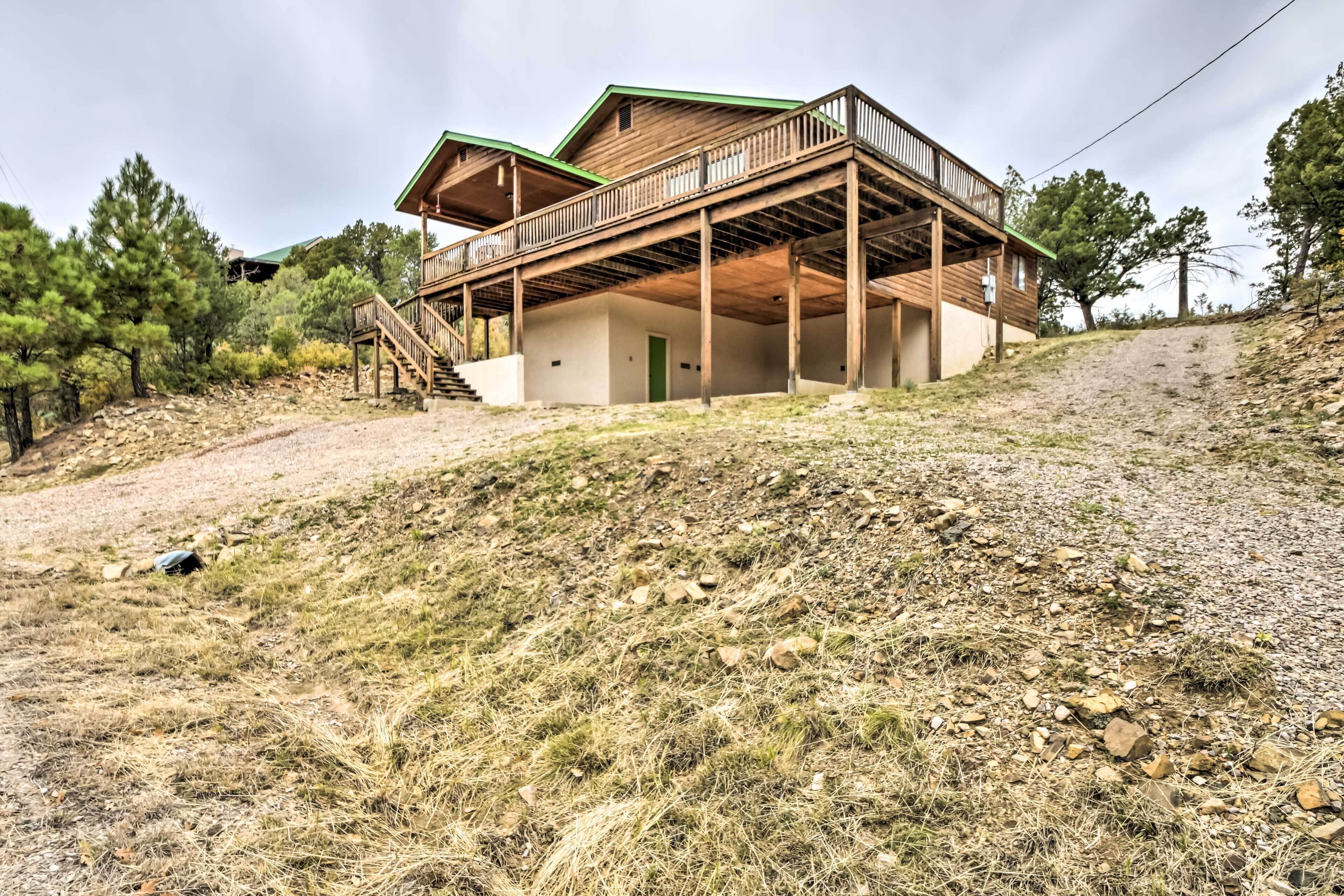 Eine Holzhütte mit Balkon, gelegen an einem Hügel, mit einem Kiesweg, der zu ihr führt.