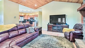 A living room with a leather sofa, a television, and a stone fireplace. - King Suite Haven Near Dale Hollow Lake & Boat Slip (Burkesville)