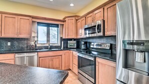 A modern kitchen with wooden cabinets, stainless steel appliances, and a granite countertop. - King Suite Haven Near Dale Hollow Lake & Boat Slip (Burkesville)