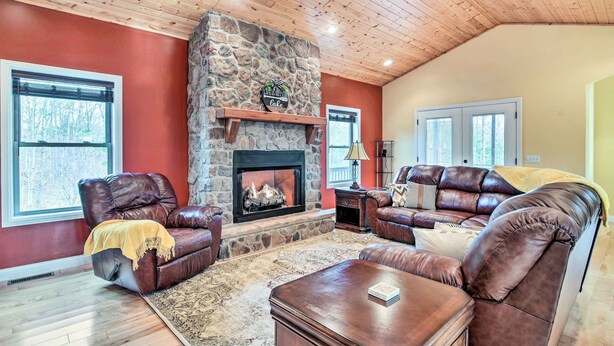A cozy living room with leather sofas, a stone fireplace, and wooden flooring. - King Suite Haven Near Dale Hollow Lake & Boat Slip (Burkesville)