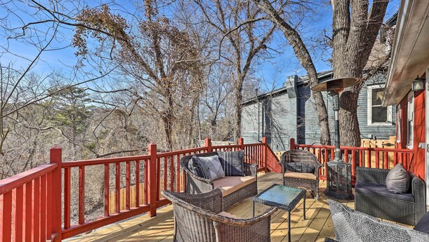 Eine Terrasse mit Korbmöbeln, einem roten Geländer und einem Schornstein.