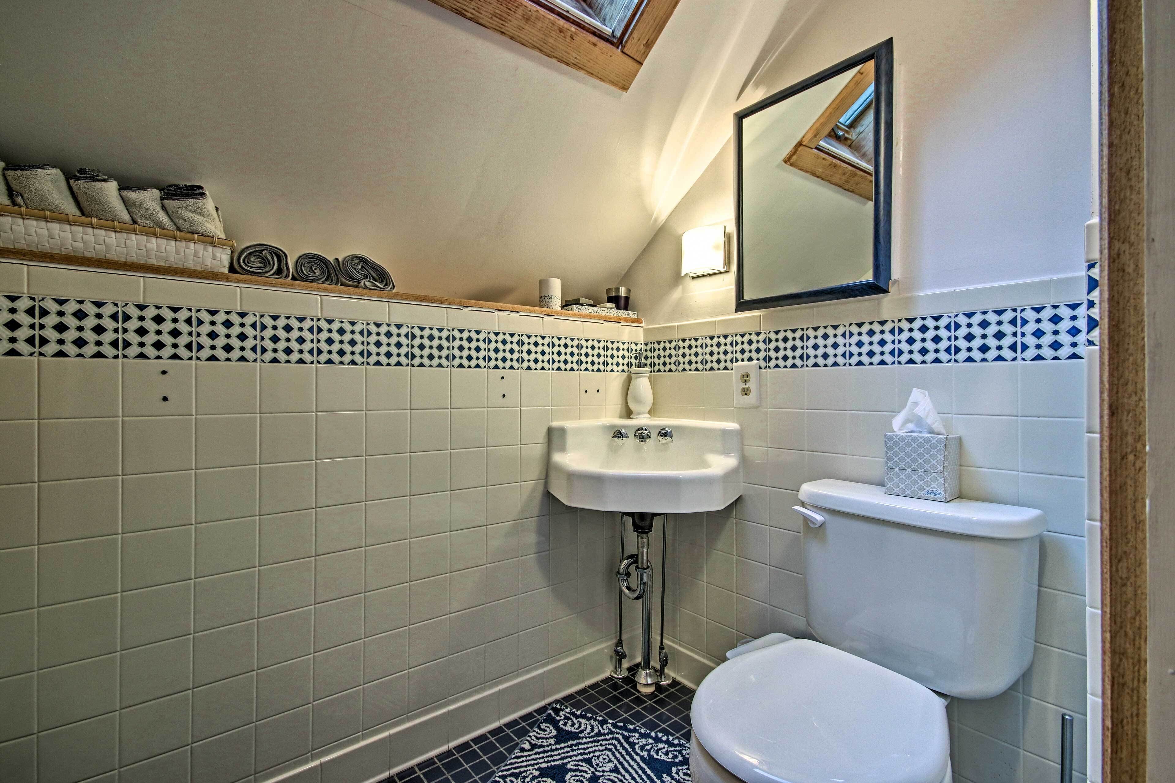 Et badeværelse med en hvid vask, toilet og et spejl over vasken.