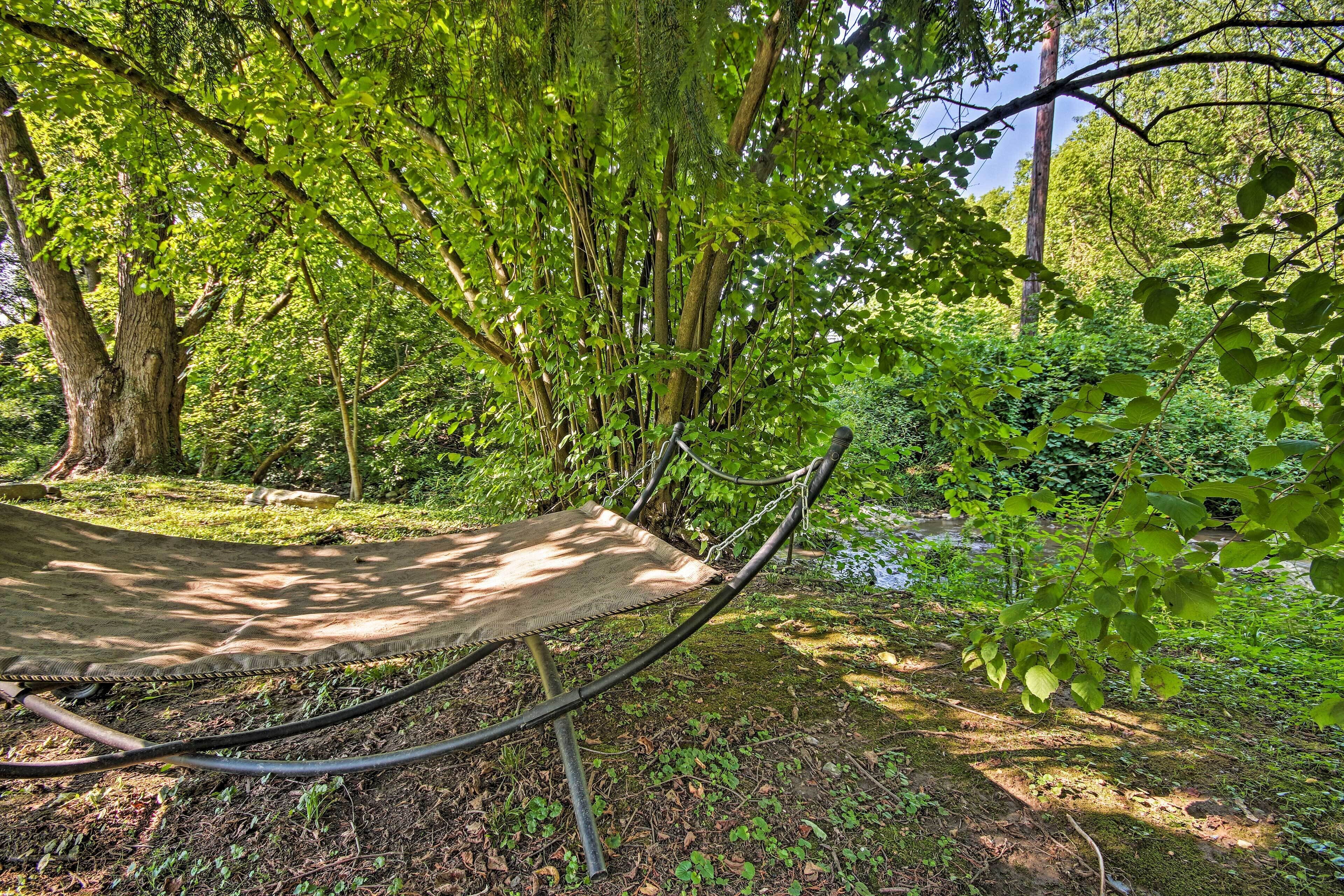 A hammock in a forested area with a river in the background.
