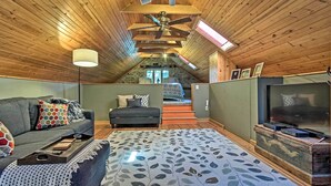 Une chambre confortable située sous les toits, avec un plafond en pente, un grand lit, une télévision et une cheminée.