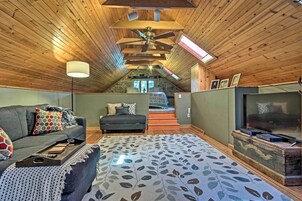 A cozy attic bedroom with a sloped ceiling, a large bed, a TV, and a fireplace.