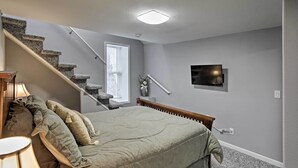 Une chambre à coucher avec un lit, une lampe, un téléviseur et un escalier.