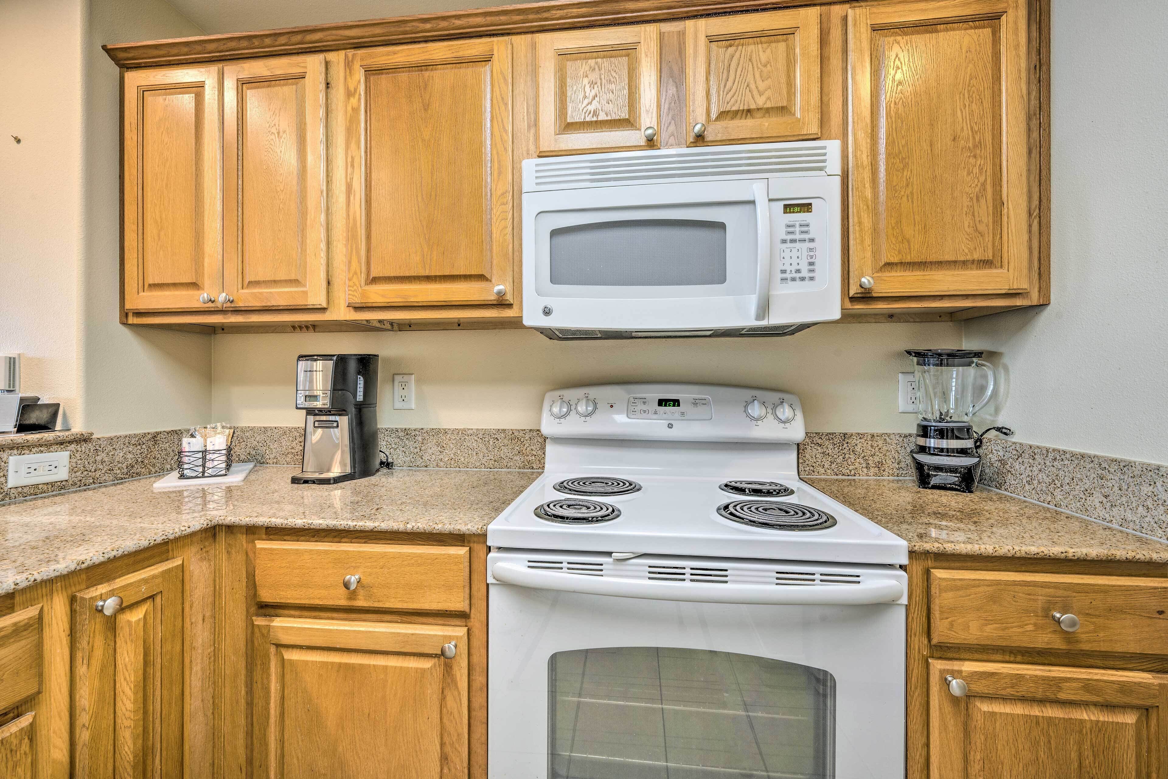 A kitchen with wooden cabinets, a white stove, a microwave, and a coffee maker.