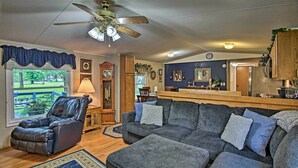 A living room with a grey sectional sofa, a leather recliner, a ceiling fan, and a view of the outdoors. - Hot Tub & Deck: Tranquil Home Near Grand Lake (Grove)