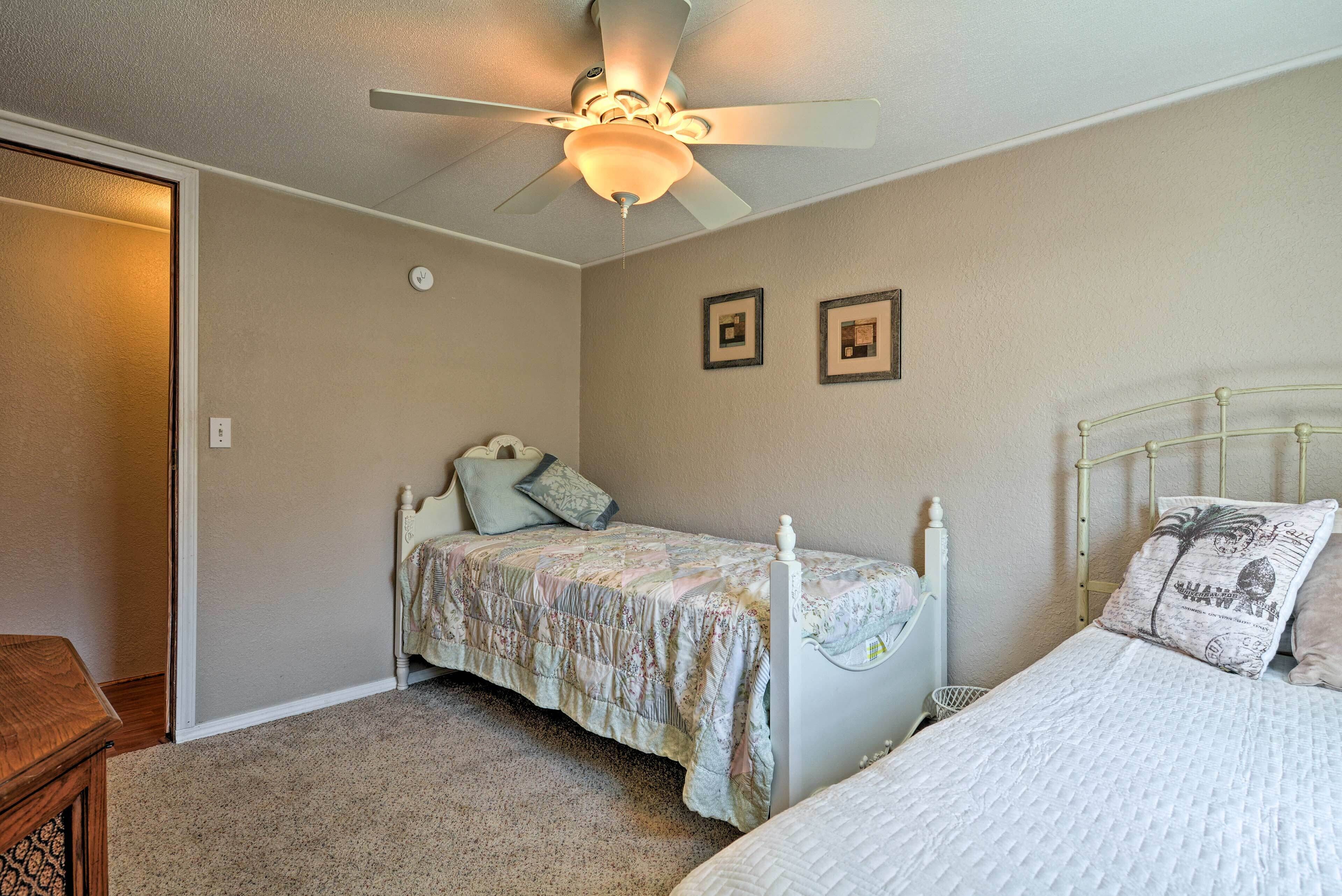 A bedroom with two single beds, a ceiling fan, and a door.