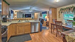 A spacious kitchen with wooden cabinets, a dishwasher, and a dining area with wooden chairs and a table. - Hot Tub & Deck: Tranquil Home Near Grand Lake (Grove)