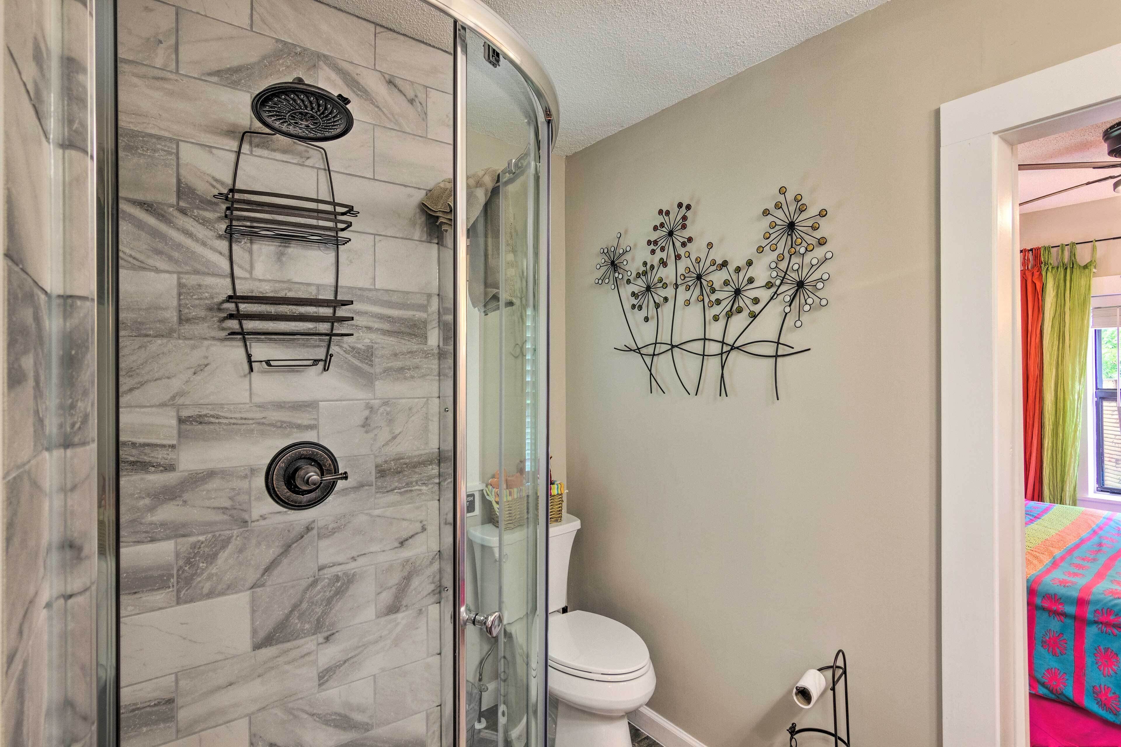 A bathroom with a glass-enclosed shower, a toilet, and a wall-mounted sink.