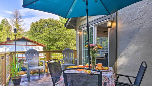 Une terrasse extérieure couverte, avec une table dressée pour les repas, entourée de chaises et dotée d’un grand parasol pour faire de l’ombre.