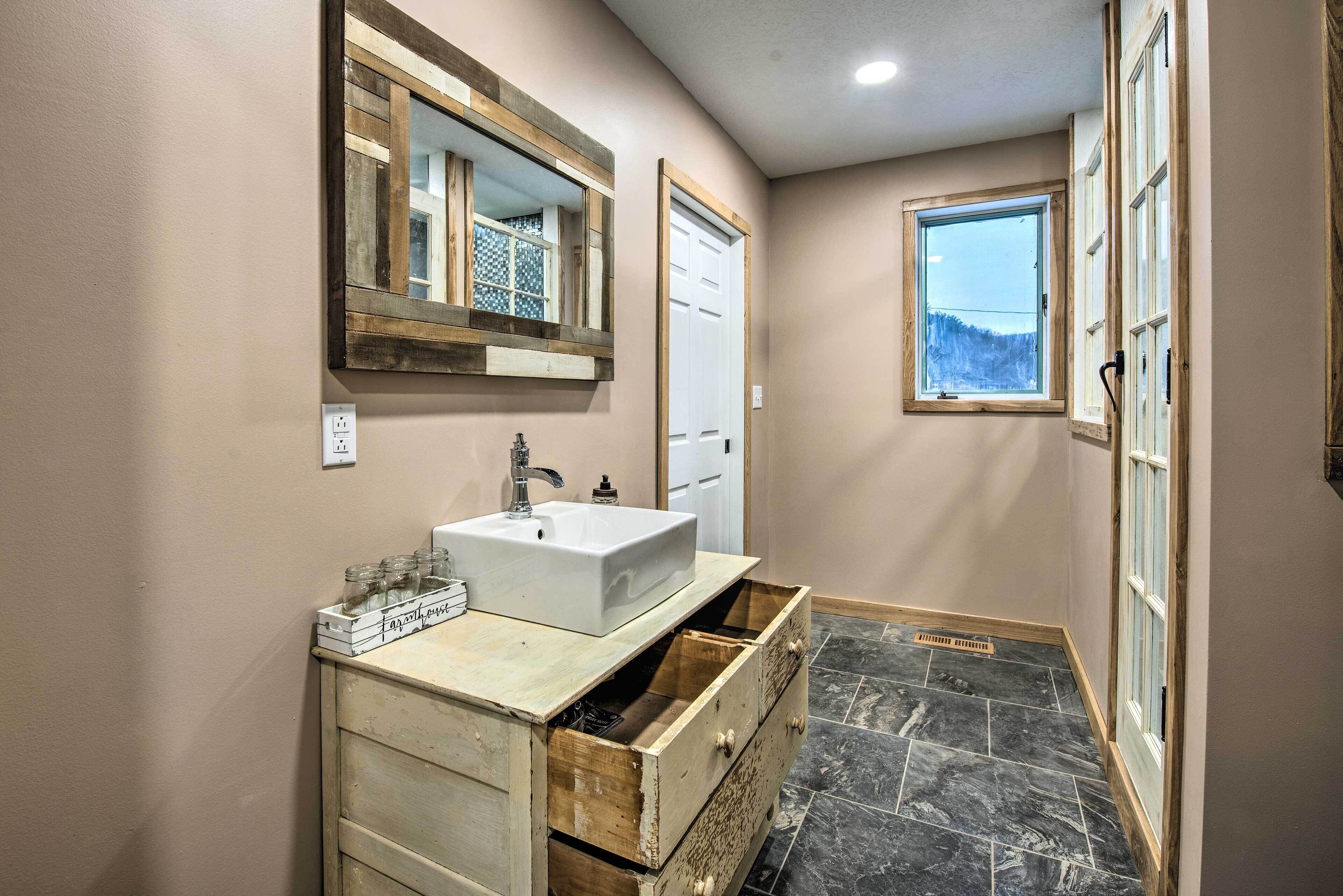 A bathroom with a white sink, wooden vanity, and a window with a view of trees.