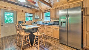 A wooden cabin kitchen with a large refrigerator, wooden chairs, and a dining table. - Peaceful Decatur Cabin w/ Grill & Fire Pit! (Decatur)