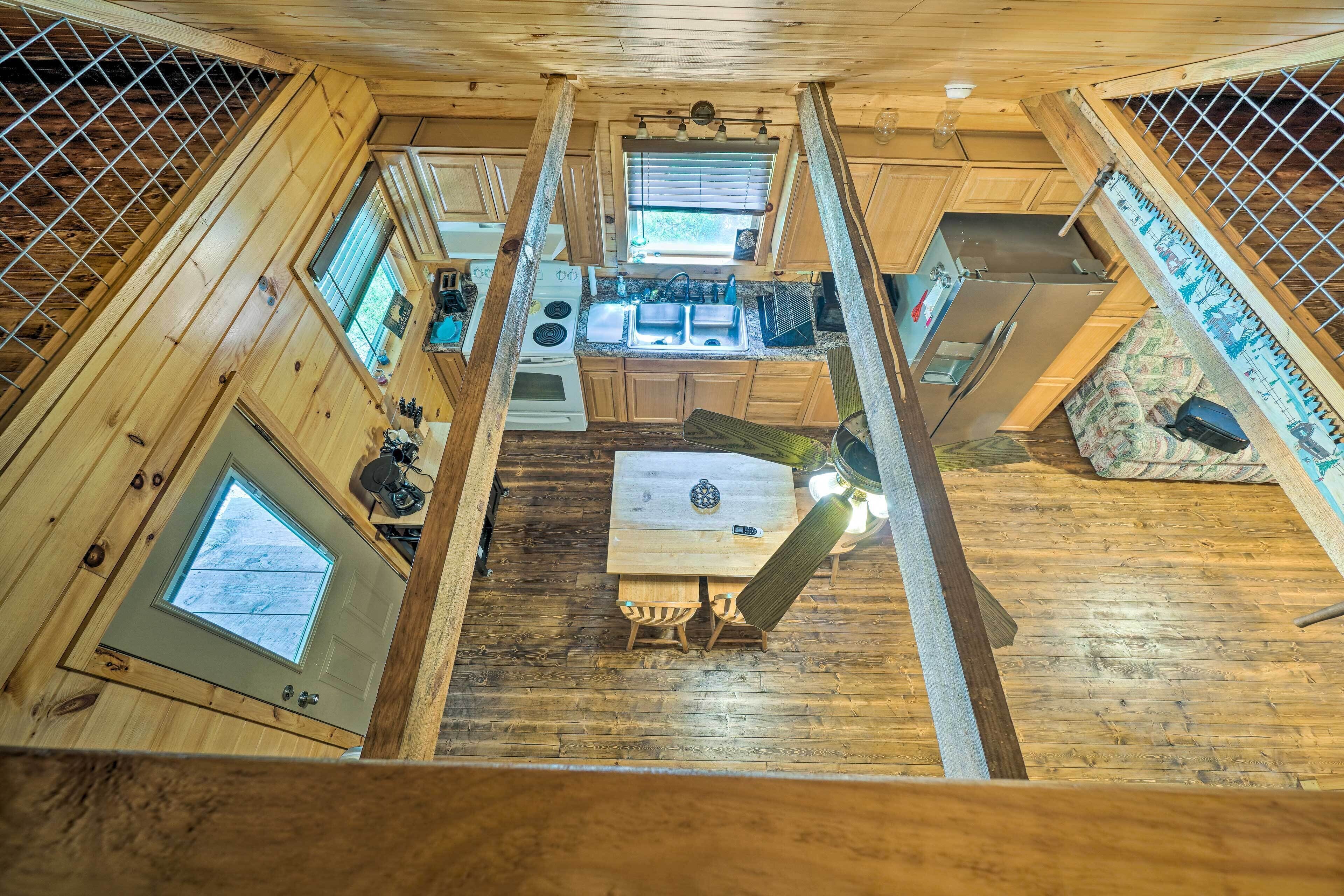 A high-ceilinged wooden cabin kitchen with a central island, built-in appliances, and a window overlooking the outdoors.