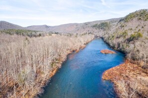 Un río serpentea por un valle boscoso, con colinas al fondo.