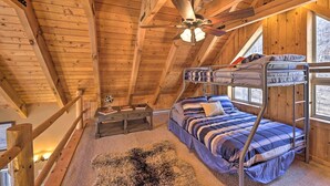 Um quarto de sótão aconchegante com beliche, escrivaninha e ventilador de teto.