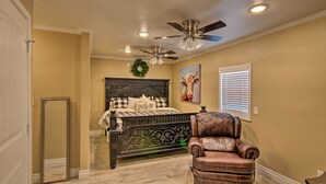 A bedroom with a bed, a ceiling fan, a wall-mounted wreath, a window with blinds, and a leather chair. - Walk to Texas Tech! Cozy Lubbock Gem w/ Patio (Lubbock)