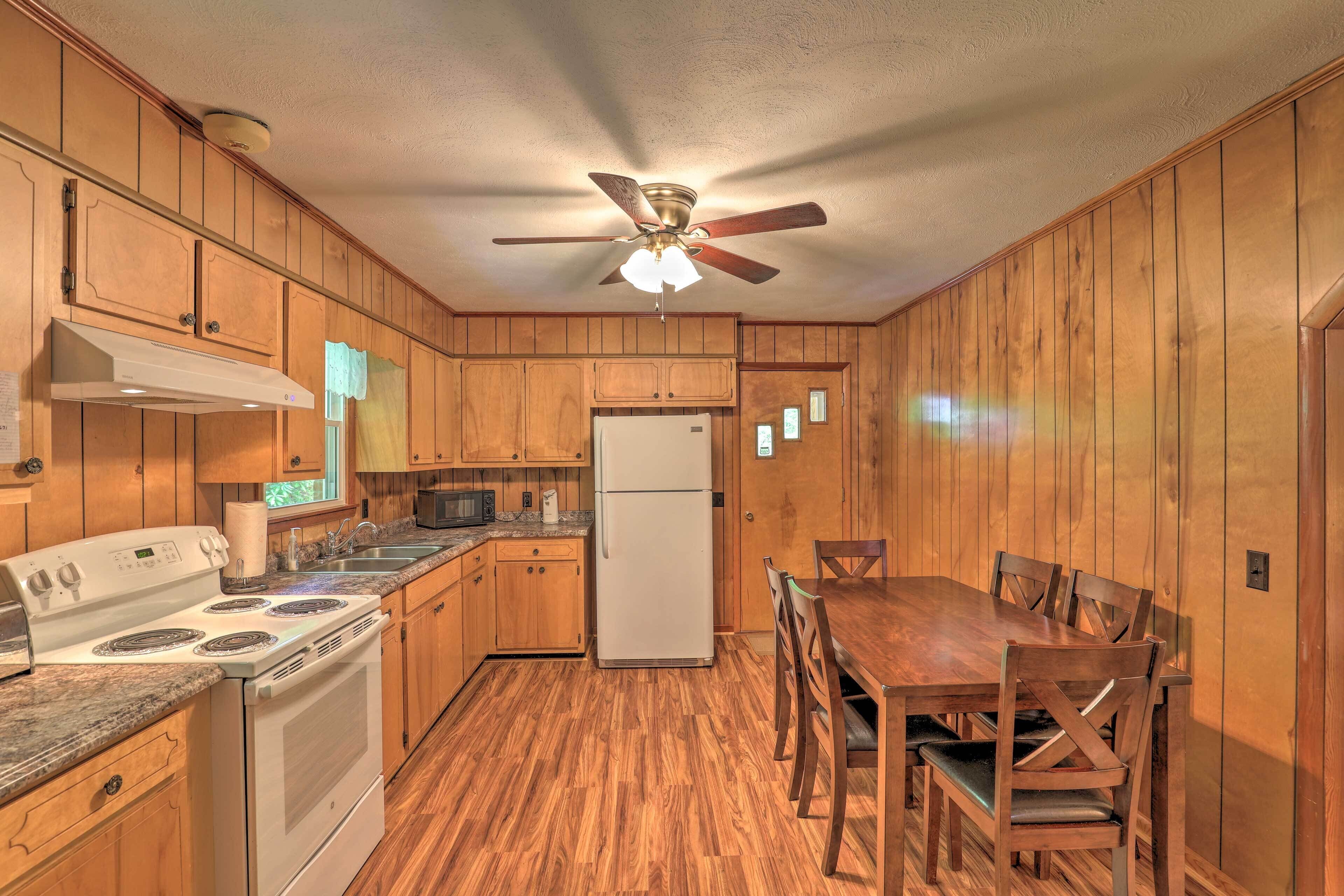 A kitchen with wooden cabinets, a white stove, a refrigerator, and a dining table with chairs.