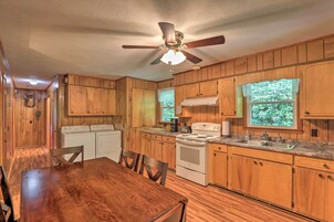 Una cocina de madera con una mesa de comedor, sillas, una estufa, un lavamanos y un ventilador de techo.