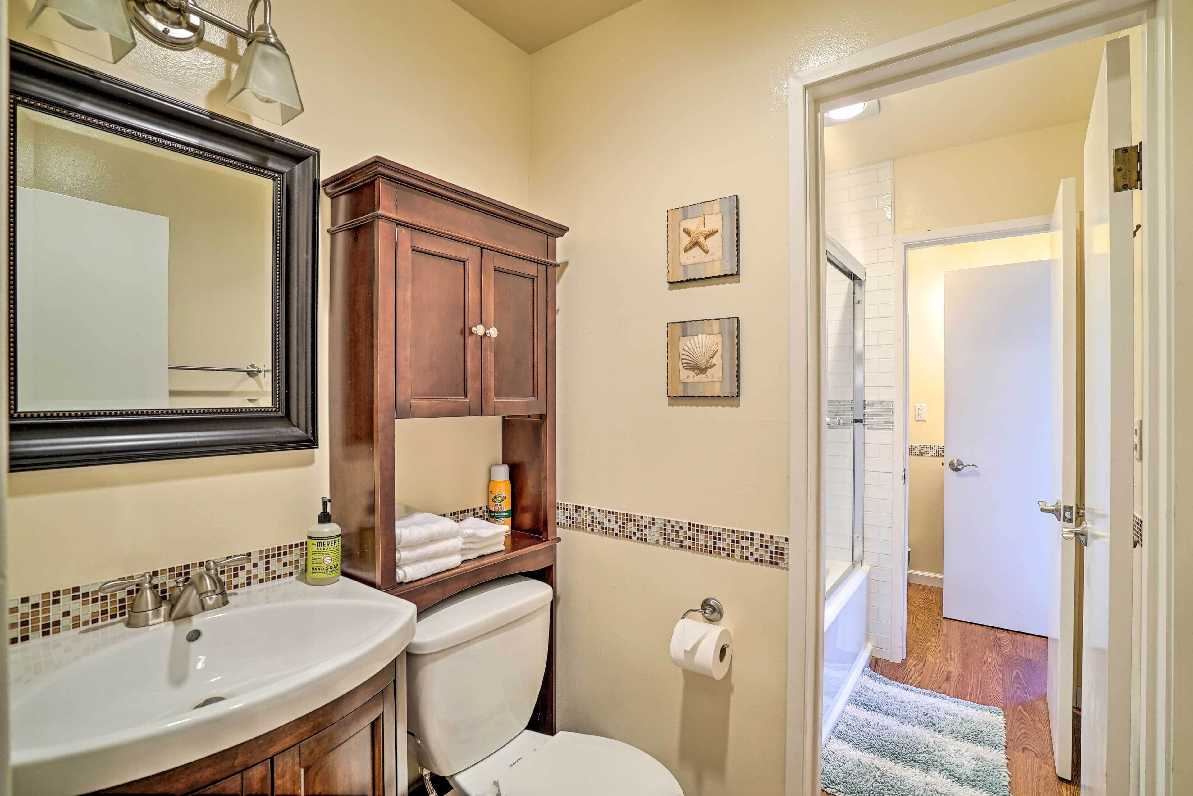 A bathroom with a sink, mirror, cabinet, toilet, and decorative wall tiles.