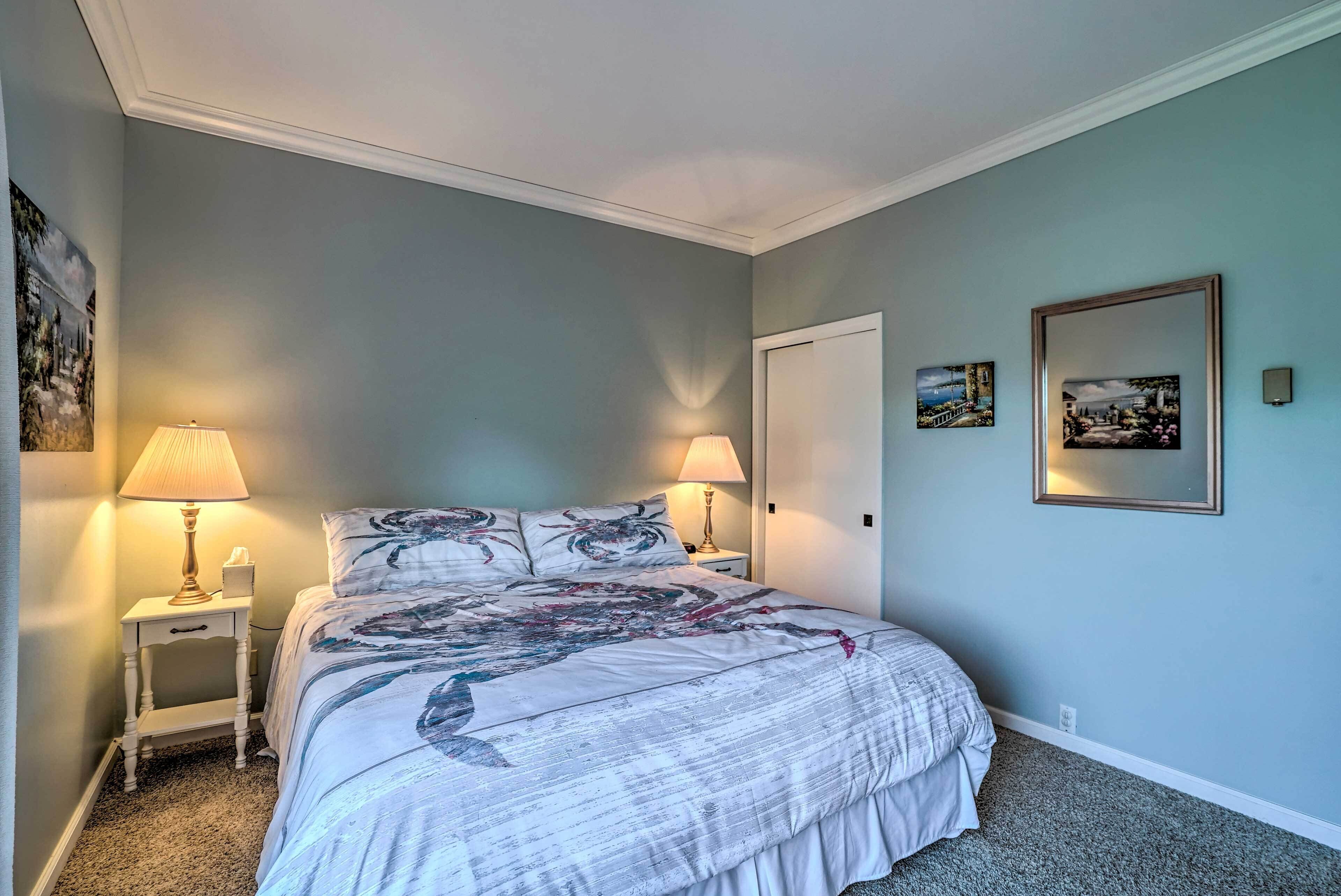 A bedroom with a bed, two bedside lamps, a nightstand, and two framed pictures on the wall.