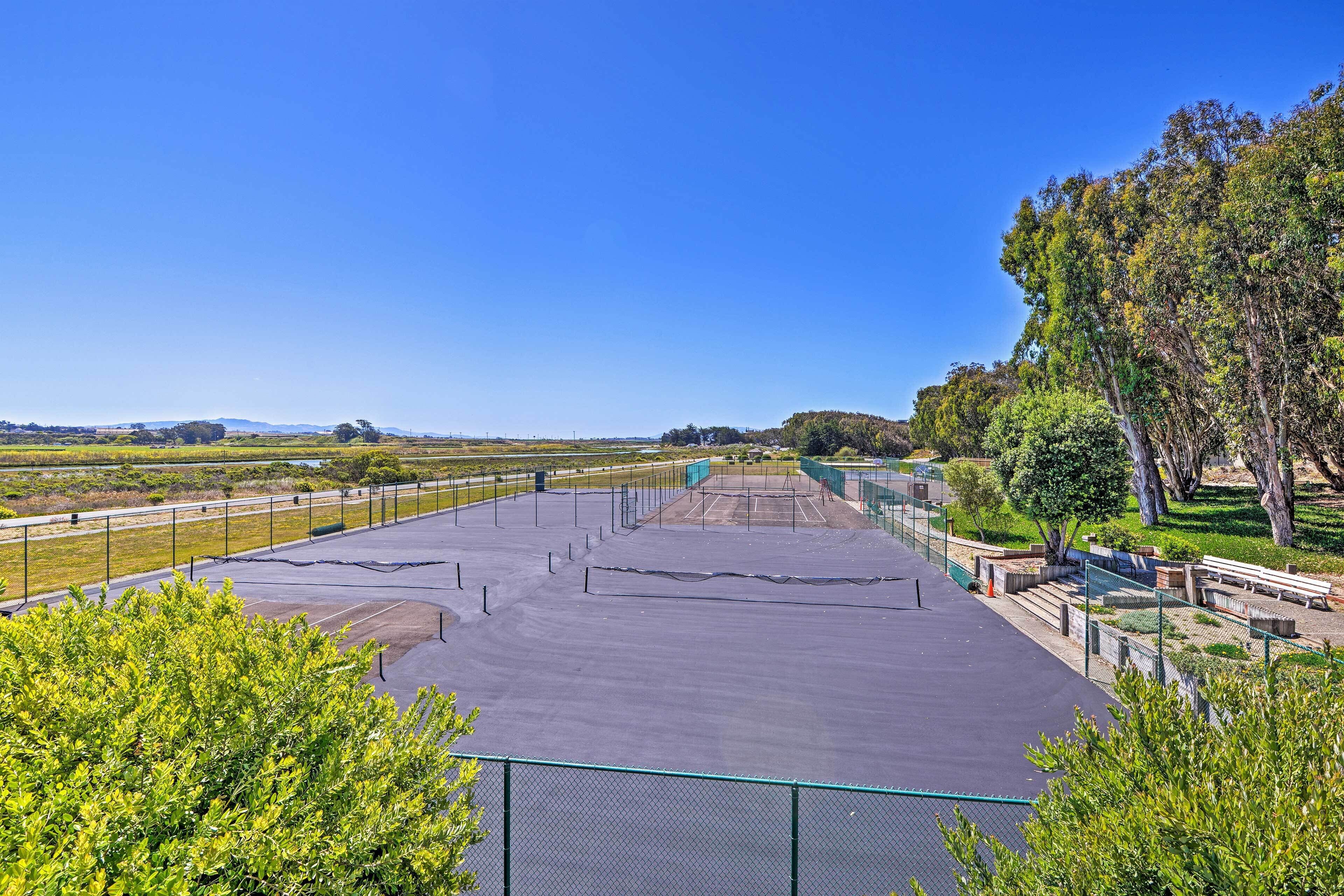Un court de tennis avec un filet, entouré de verdure et d’arbres.