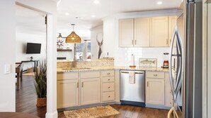 A modern kitchen with light-colored cabinets, a stainless steel refrigerator, and a built-in dishwasher.