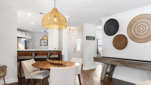 A dining area with a round table, chairs, and a hanging light fixture.