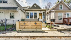 Une maison à deux étages avec un porche à l’avant, une clôture en bois décorée de drapeaux américains et une boîte aux lettres.