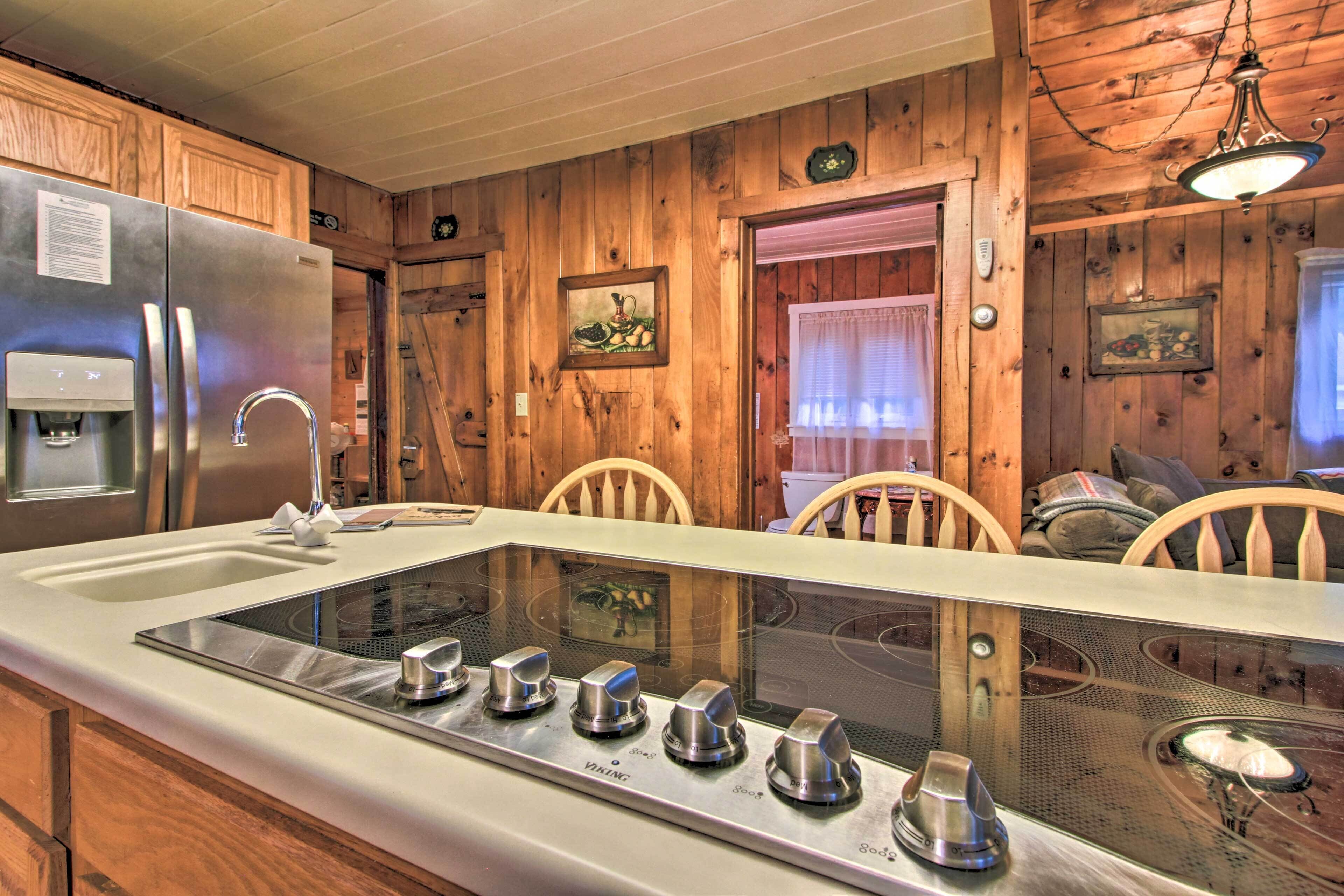 A kitchen with wooden walls, a stainless steel refrigerator, a built-in stove, and a water dispenser.