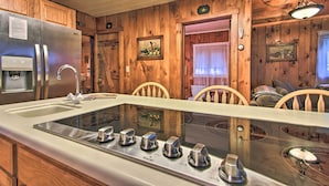 A kitchen with wooden walls, a stainless steel refrigerator, a built-in stove, and a water dispenser. - Ludlow Home w/ Hot Tub, Near Okemo Resort! (Ludlow)