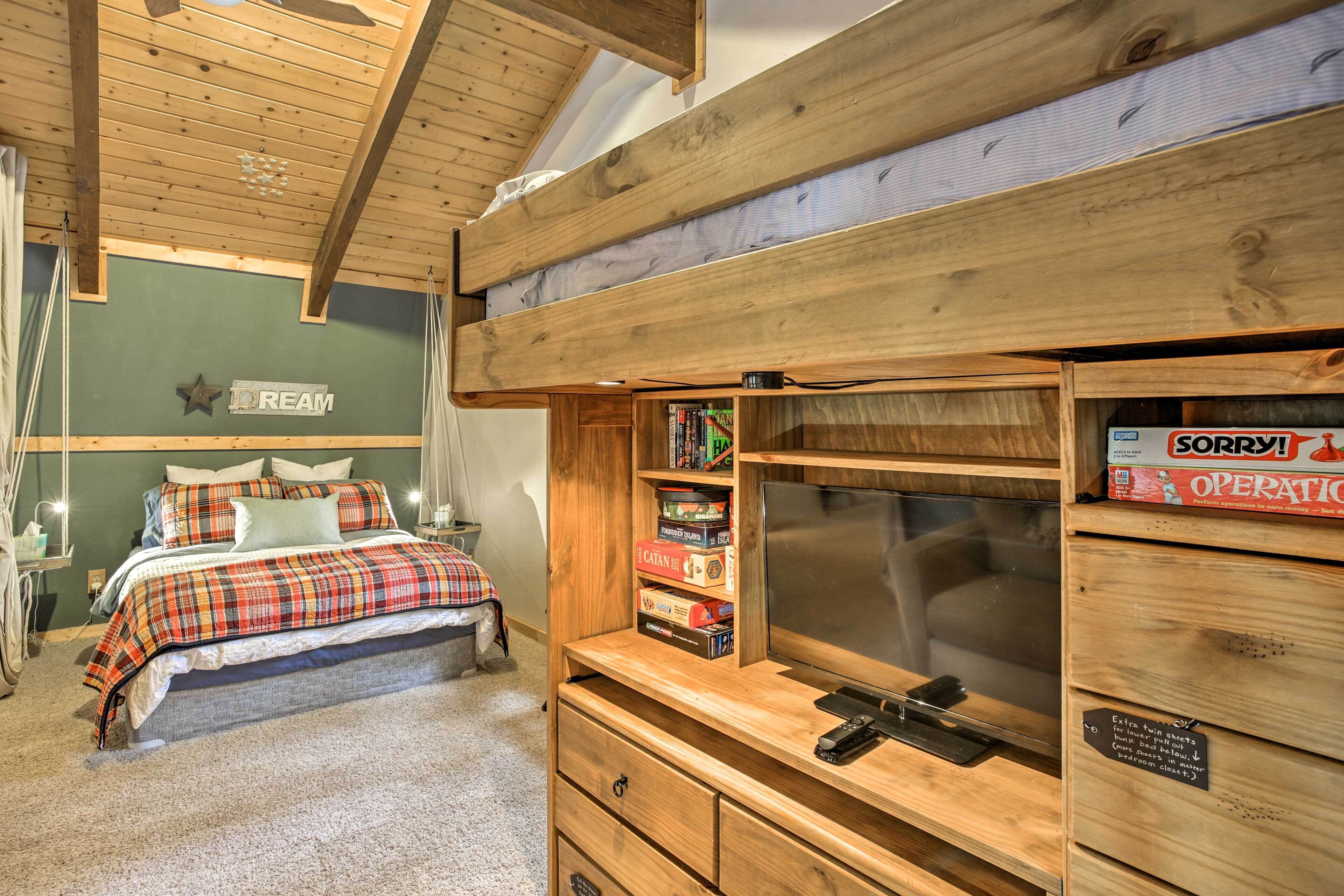 Une chambre avec un lit superposé, une tête de lit en bois, une télévision et une bibliothèque contenant des jeux de société.