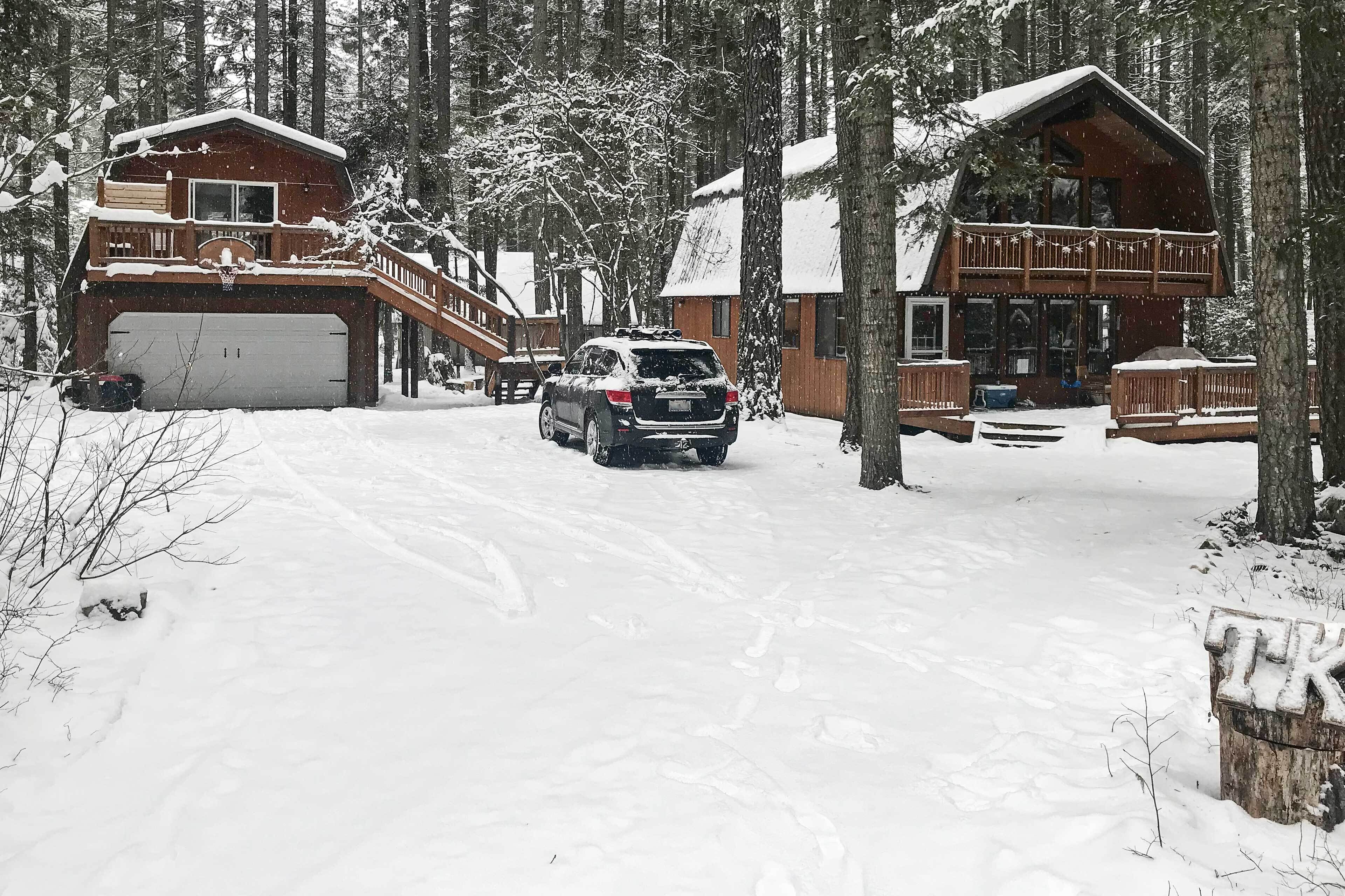 A cabin with a garage, a deck, and a covered porch.
