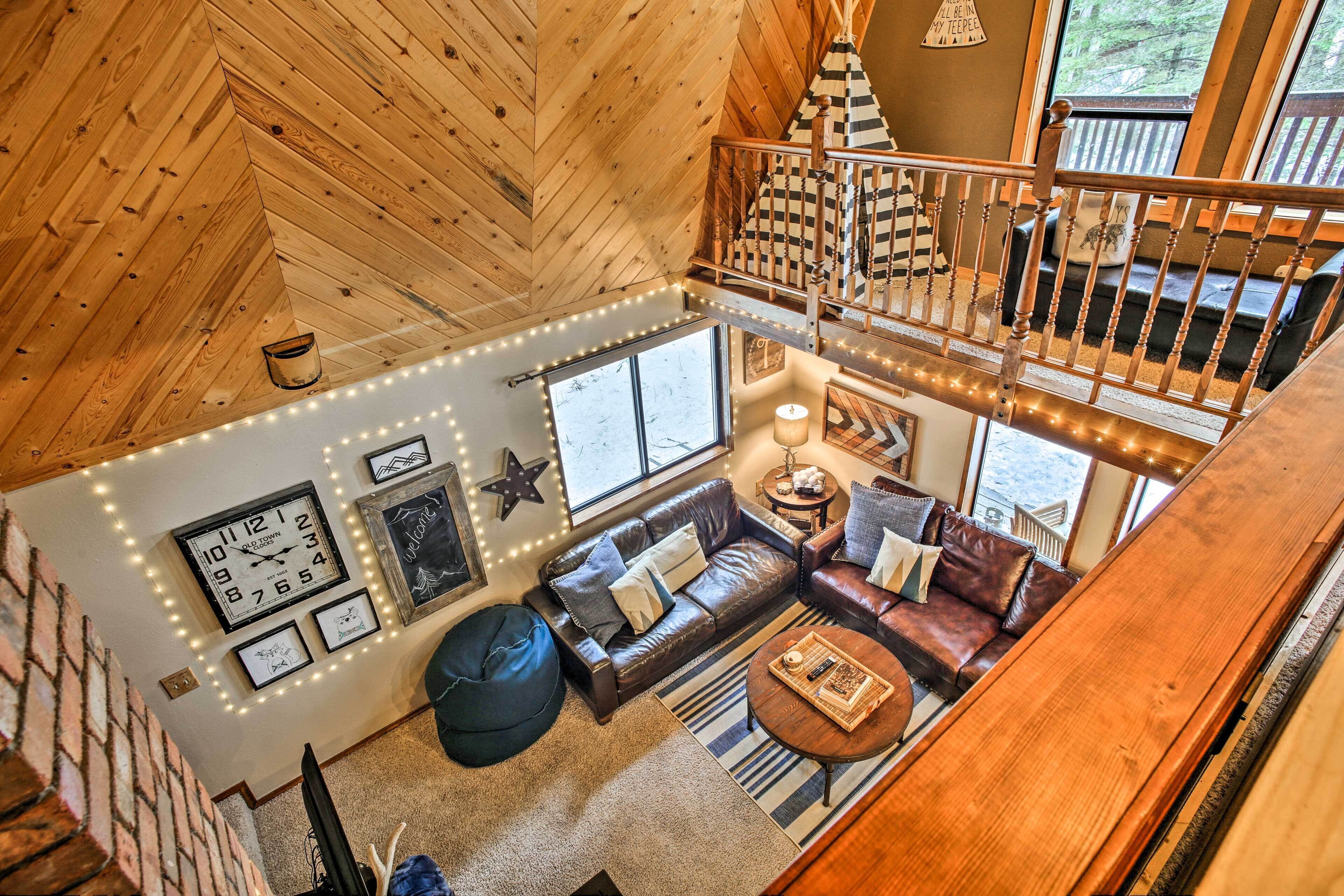Interior acogedor de una cabaña con habitación en entrepiso, sala de estar con sofá y mesa de centro, y escalera de madera.