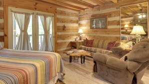 A log cabin interior with a bed, sofa, armchair, and a mirror. - 3 Mi to Natl Park: Townsend Apt on Little River! (Townsend)