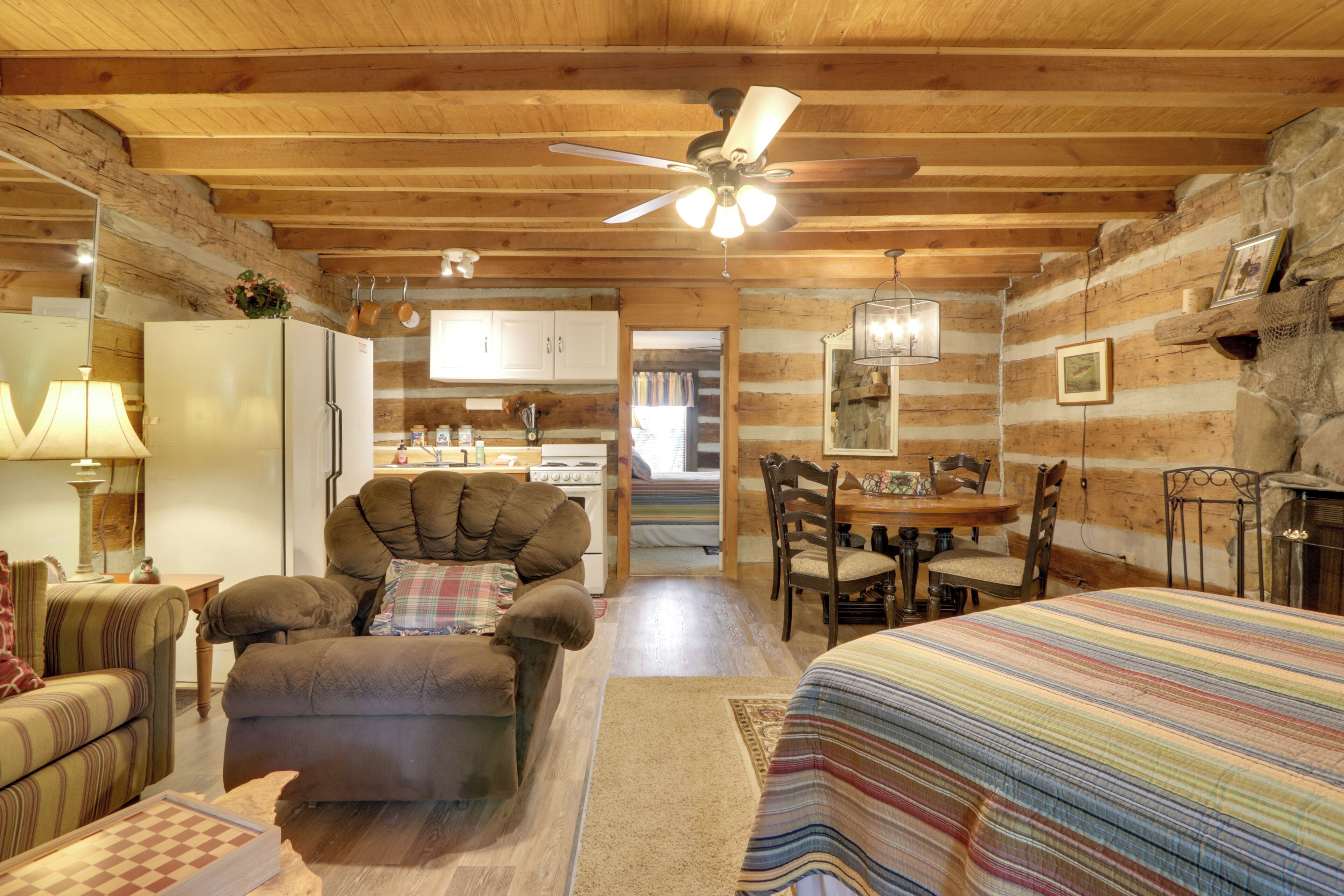 A cozy log cabin interior with a dining area, kitchen, and a large armchair.