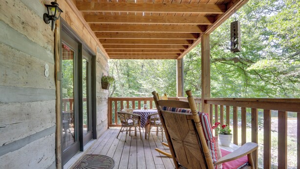 A wooden porch with a table and chairs, a door, and a window overlooking greenery. - 3 Mi to Natl Park: Townsend Apt on Little River! (Townsend)