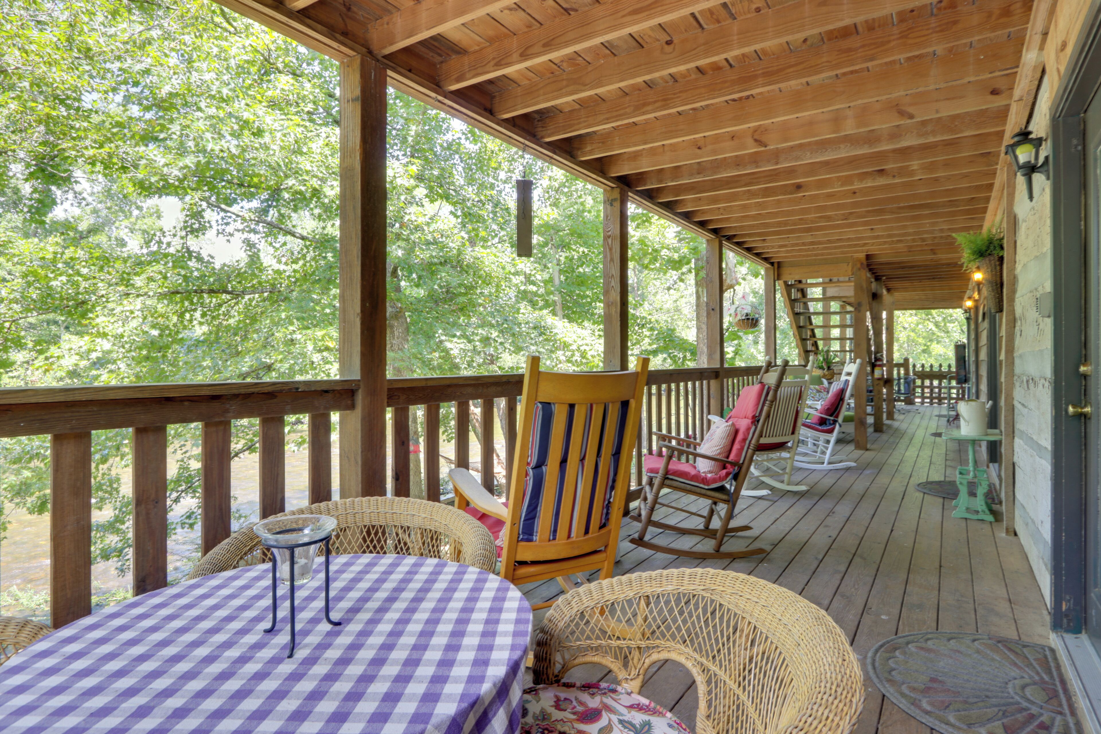 A covered outdoor deck with wicker furniture and a checkered tablecloth.