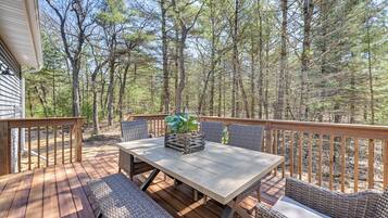 A wooden deck with a table and chairs, surrounded by trees.
