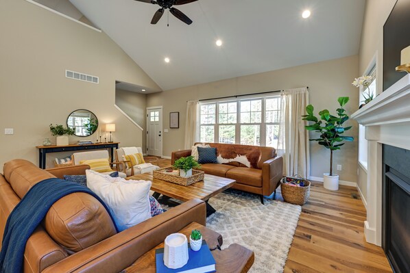 A spacious living room with a brown leather sofa, a wooden coffee table, and a fireplace. - Chic Wisconsin Retreat w/ Deck, Grill & Fire Pit! (Wisconsin Dells)