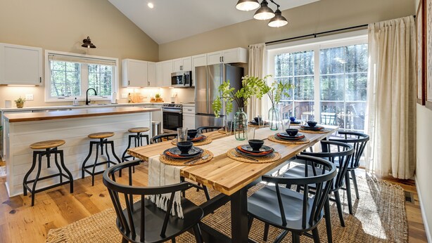A modern kitchen with a wooden island, bar stools, and a dining table set for six. - Chic Wisconsin Retreat w/ Deck, Grill & Fire Pit! (Wisconsin Dells)