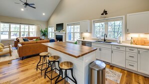 A modern kitchen with a wooden island, white cabinetry, and a ceiling fan. - Chic Wisconsin Retreat w/ Deck, Grill & Fire Pit! (Wisconsin Dells)