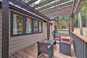 A covered deck with wicker furniture and a stone wall.