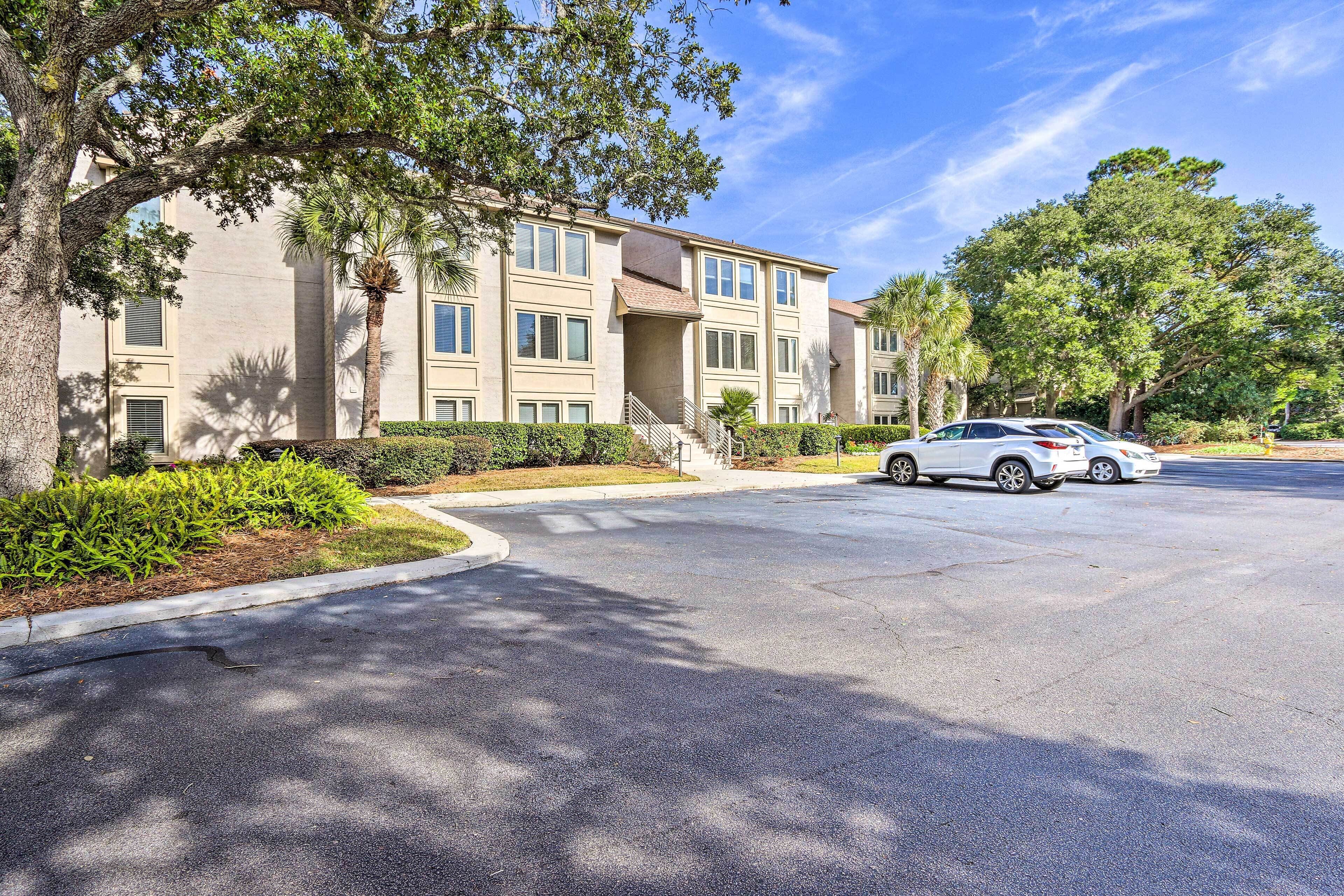A multi-story building with a parking lot and a white car parked in front.